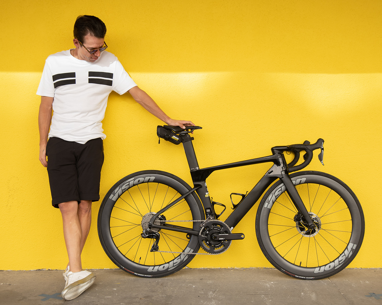 Rigoberto Uran posing with a black system six against a yellow wall at Mack Cycle in Miami.
