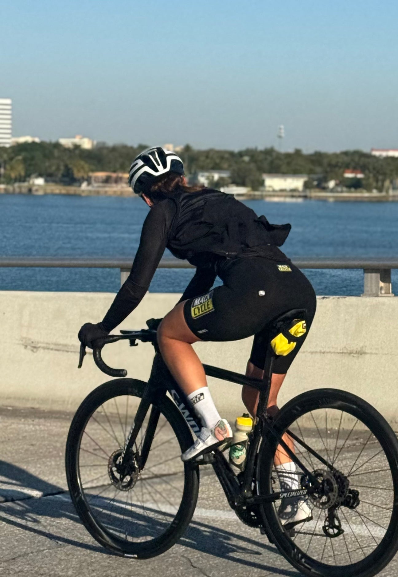 Rachel riding over the key biscayne bridge in Miami looking over the water while riding her S-Works Tarmac Project Black Road Bike